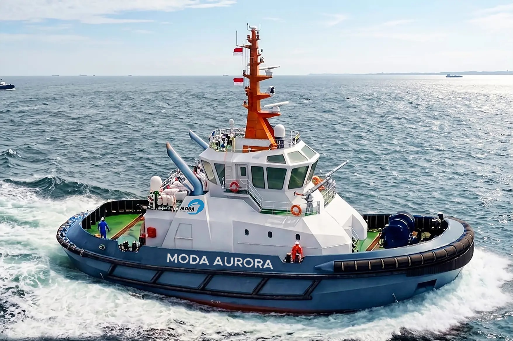 The MODA Aurora harbour tug under way at sea, with white water at her bow.